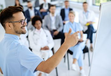 Medizinisches Team bei einer Schulung, Arzt erklärt Inhalte am Whiteboard zur Fortbildung in der Gesundheitsversorgung.