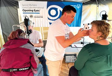 Augenuntersuchung bei Special Olympics: Arzt prüft Sehvermögen mit Handgerät im Rahmen des Programms „Opening Eyes“